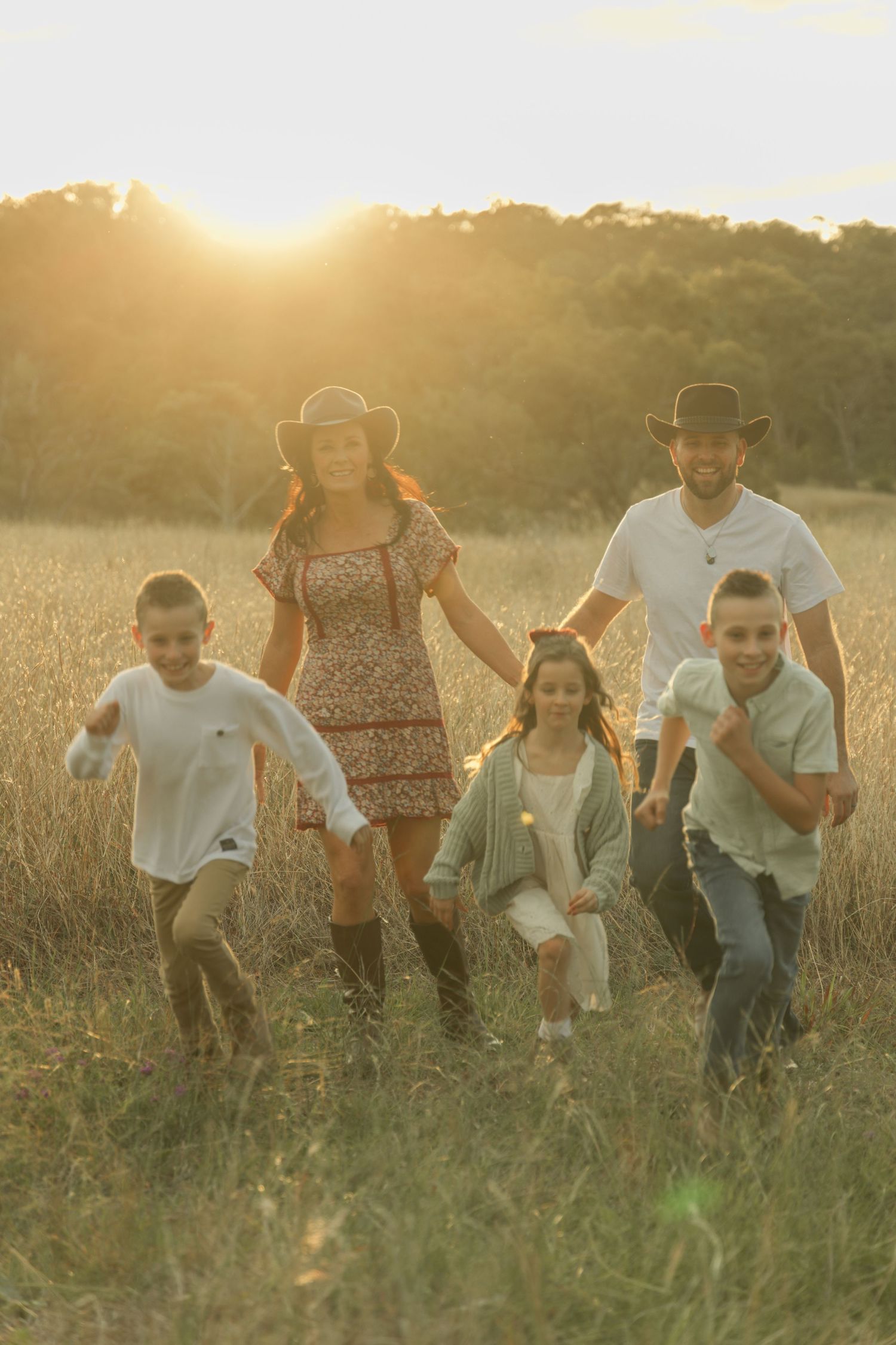 Family playing together in a sunlit field during golden hour.
