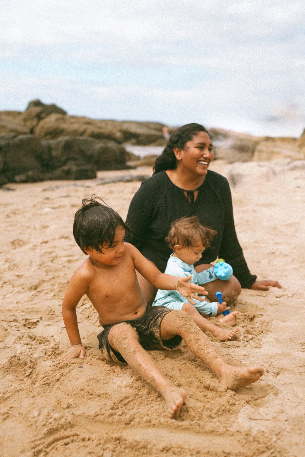 Family enjoying a playful moment together on sandy beach.