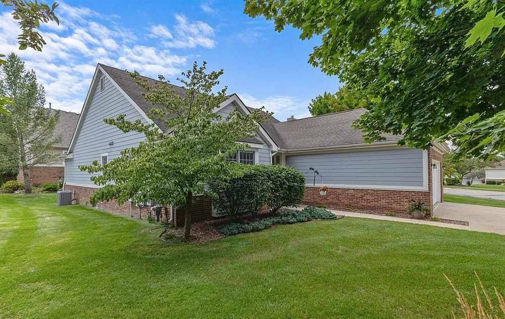 Front exterior of a gray vinyl-sided ranch home with brick accents and manicured green lawn.