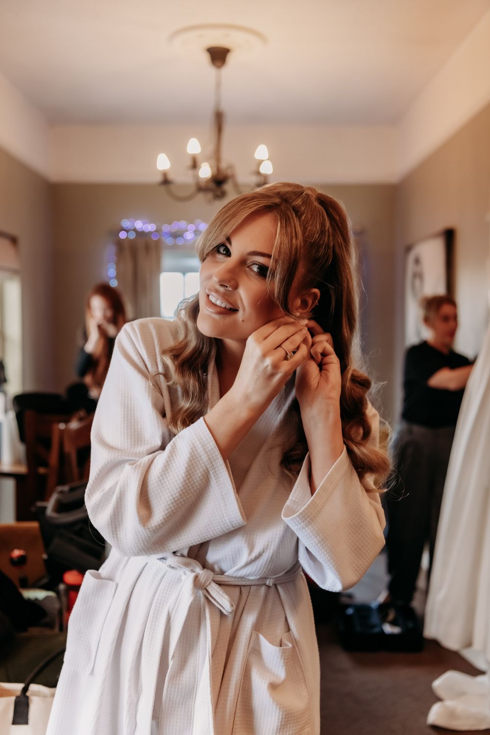 A sequence of photos showing someone in a white robe getting ready and having their makeup applied in a warm-lit room.