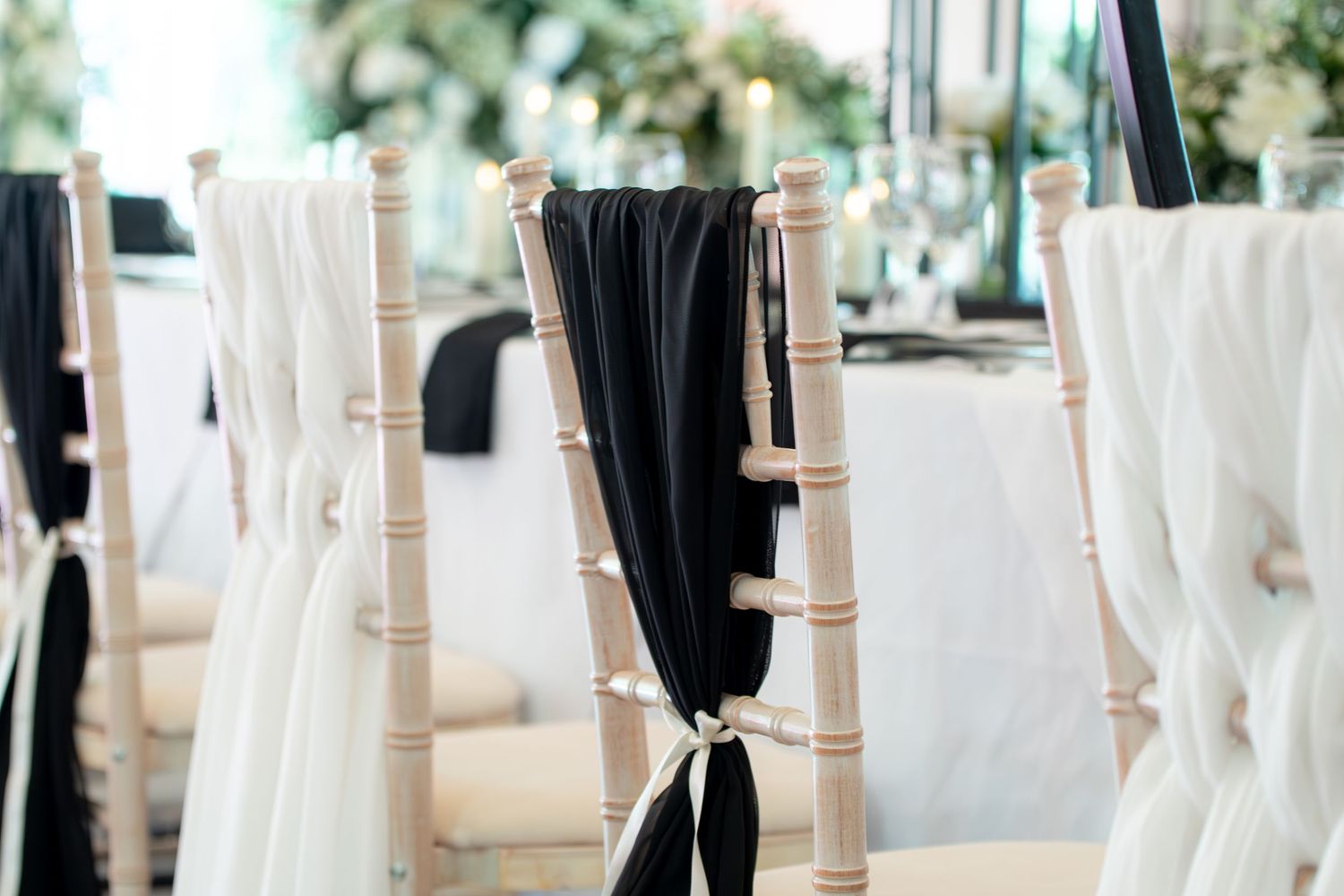 White and black chair covers arranged in rows at an elegant event venue.