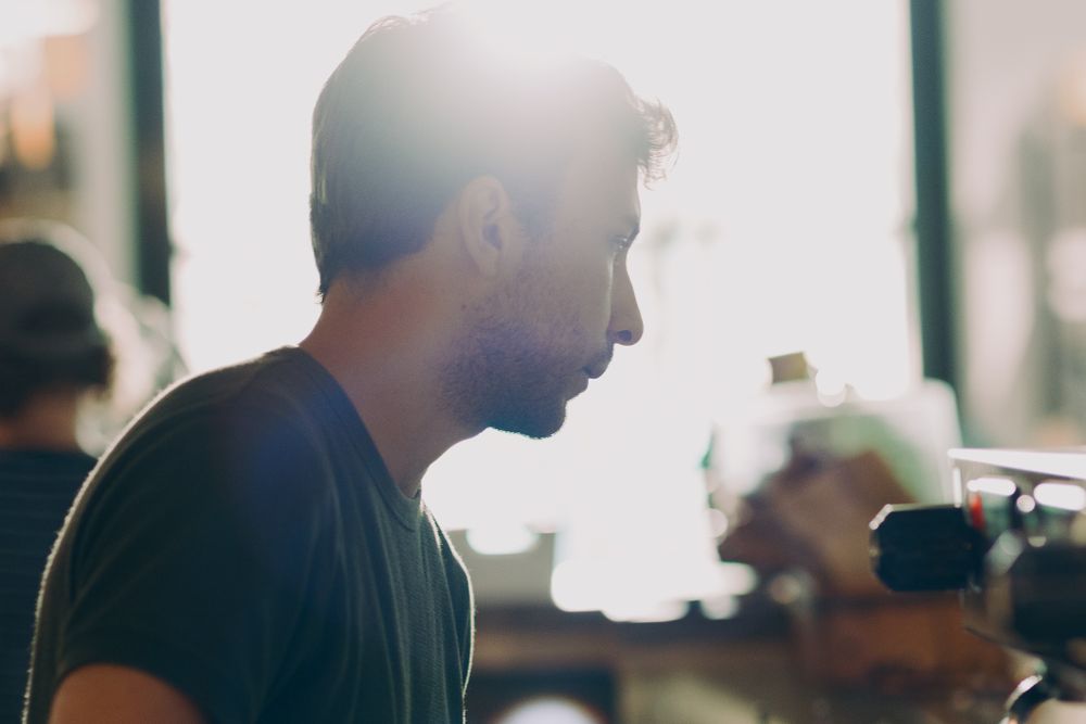 Silhouettes of diners against bright window light in a restaurant setting.