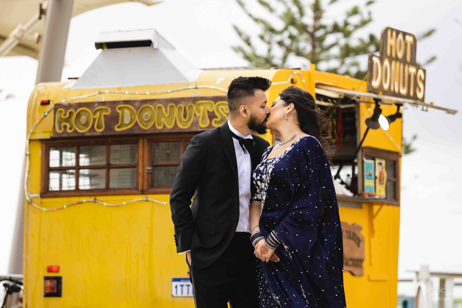 A romantic moment between a couple in front of a yellow food truck.