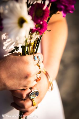 Close-up of hands holding colorful pink and white flowers against blurred background.