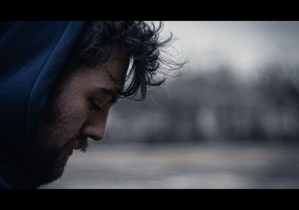 desaturated cinematic portrait of bearded man in blue hoody