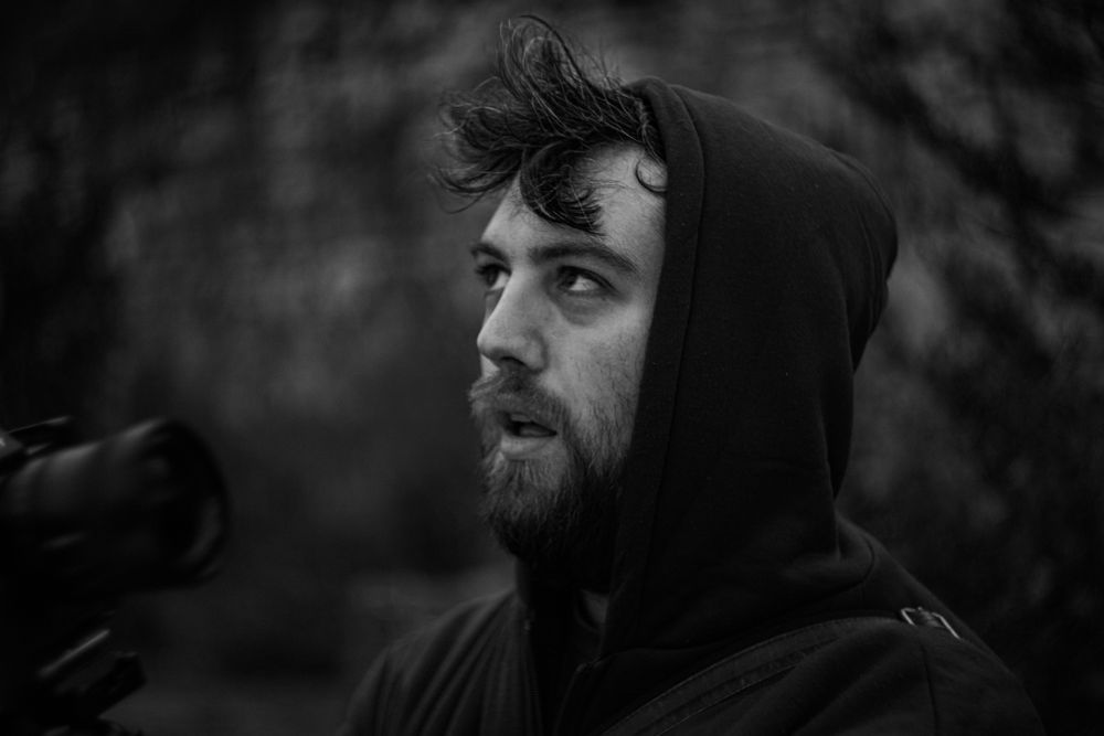 black and white image of man with beard wearing hoody