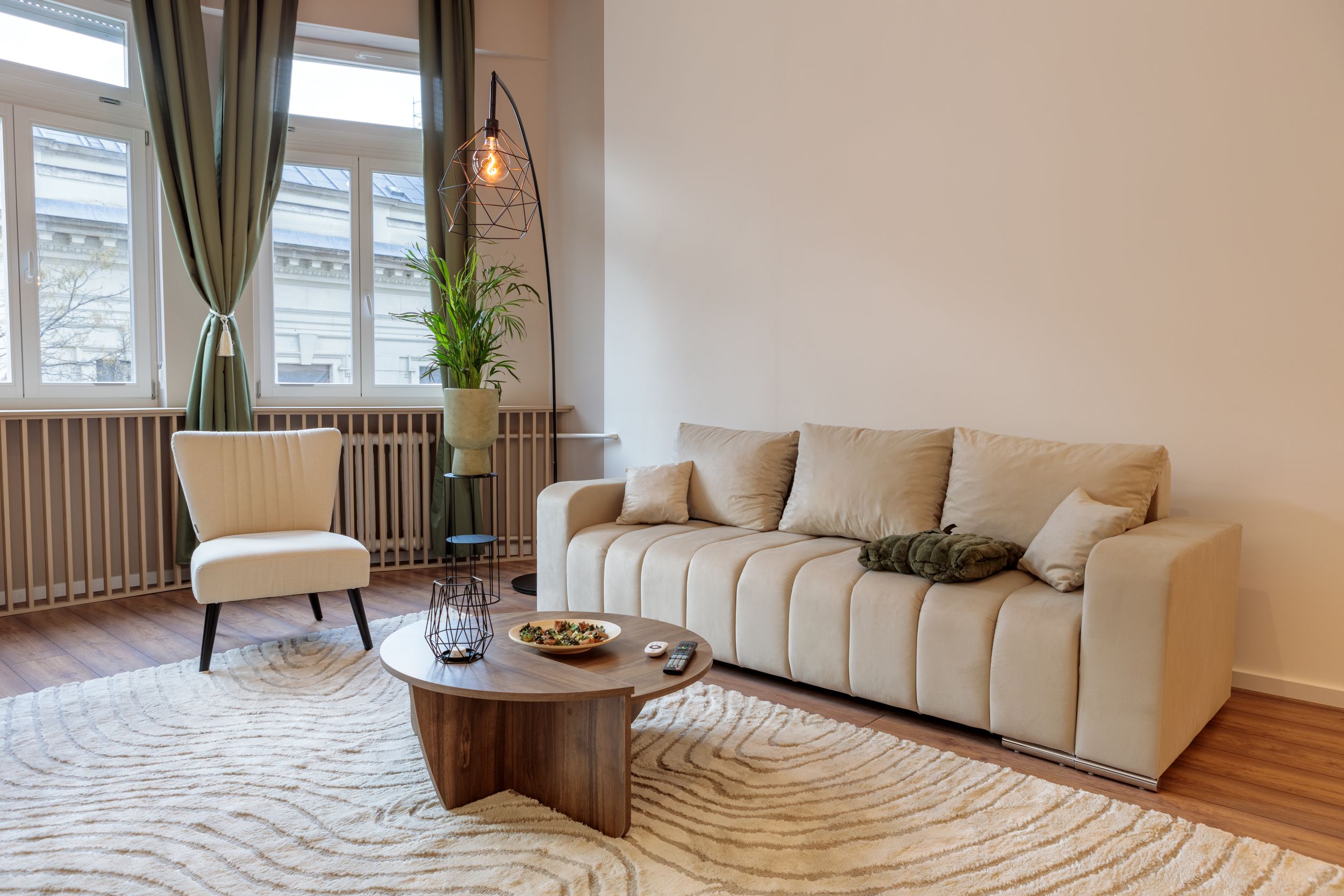 Contemporary living space with curved sofa, wooden coffee table, and green curtains.