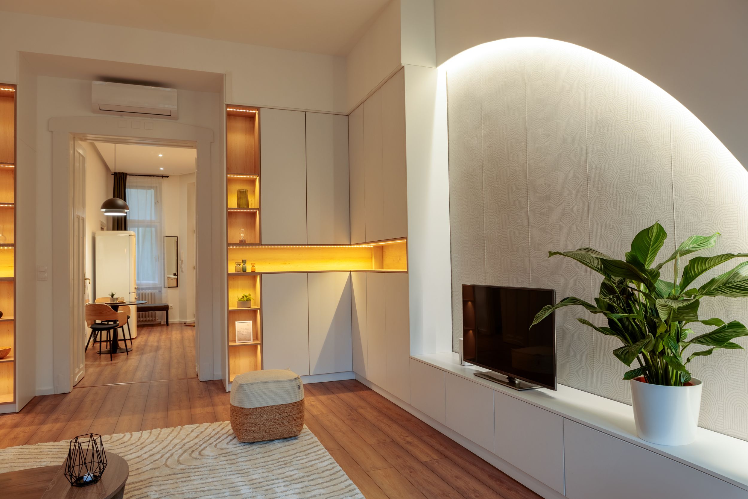 Modern interior with curved wall feature, built-in lighting, and hardwood floors.