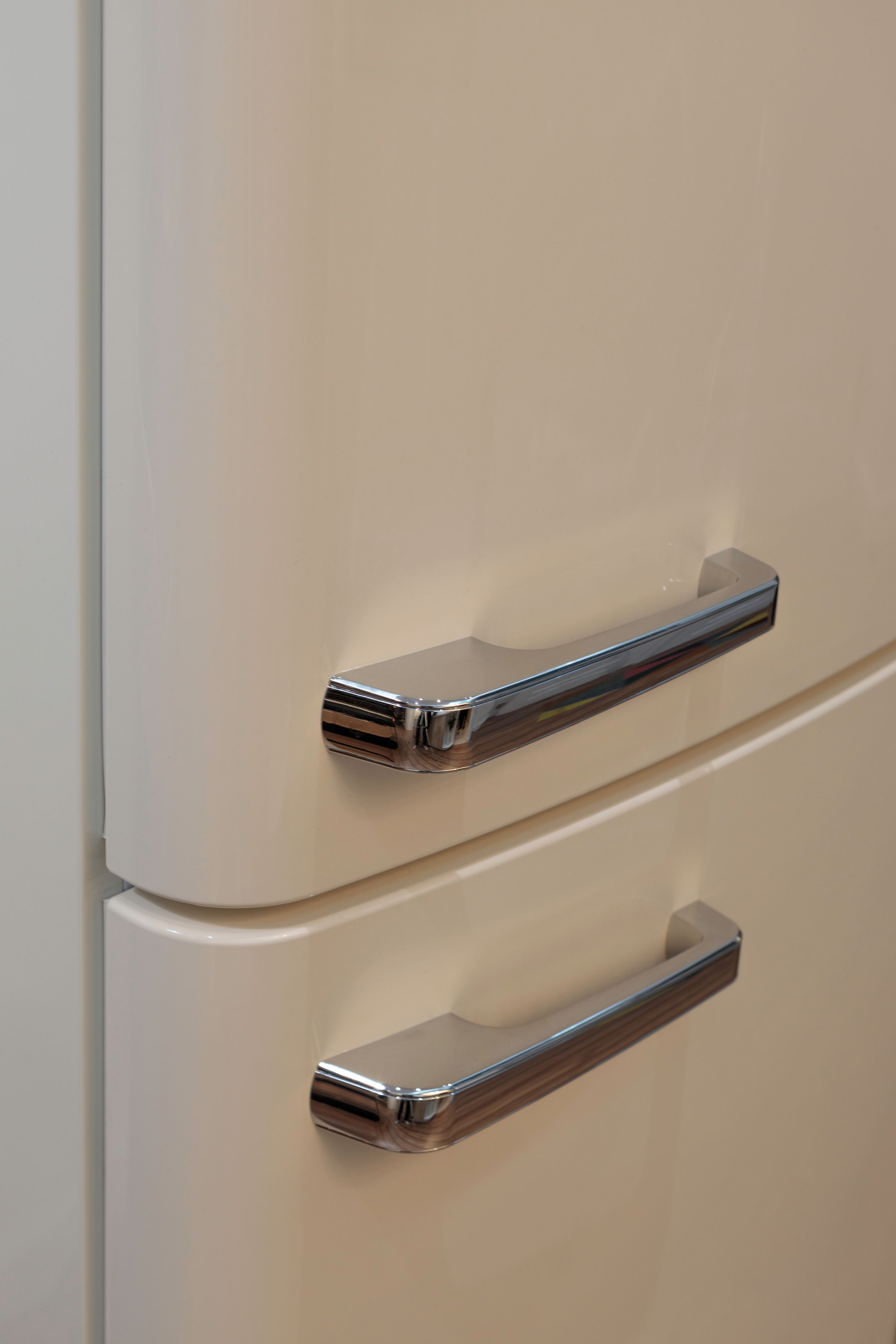 Chrome handles on a vintage-style cream colored refrigerator door.
