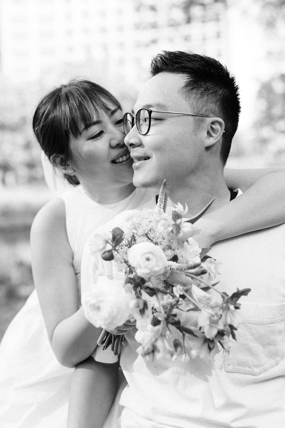 A black and white portrait capturing an intimate moment with a floral bouquet.