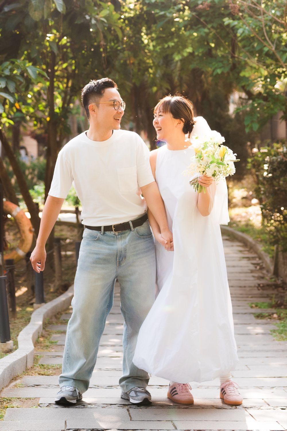 A couple sharing laughter while walking along a garden pathway.
