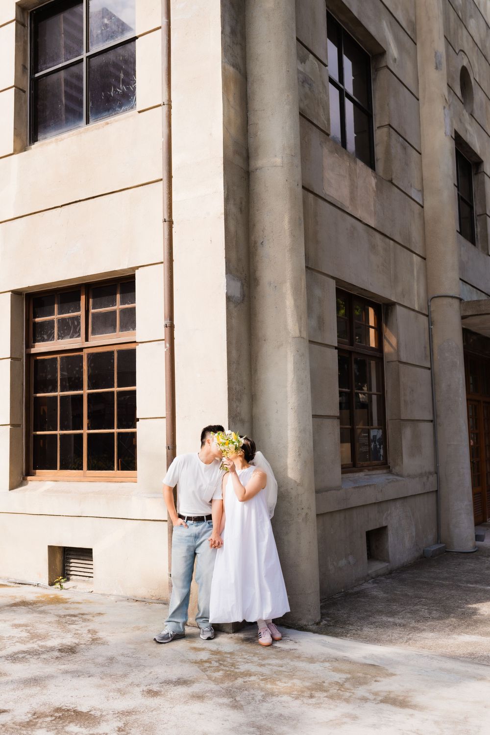 A romantic moment between a couple against a stone building wall.
