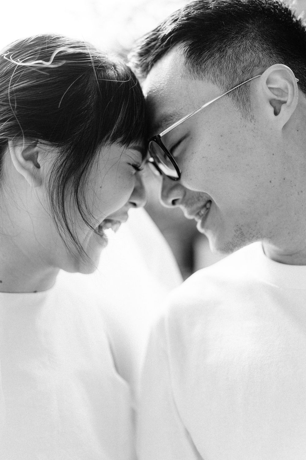 Intimate black and white portrait of a couple touching foreheads in a tender moment.
