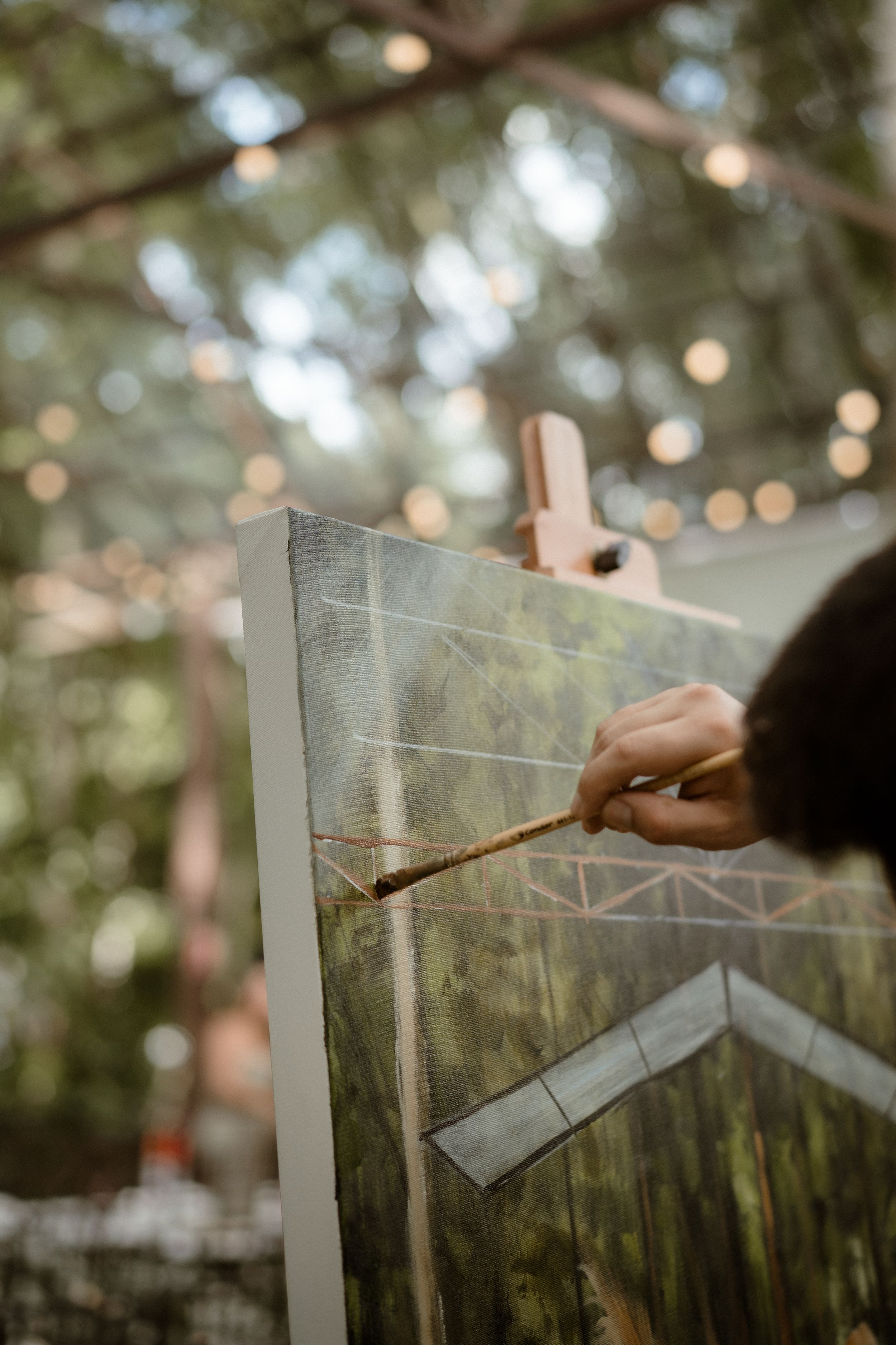 Artist painting a live wedding scene on canvas outdoors.