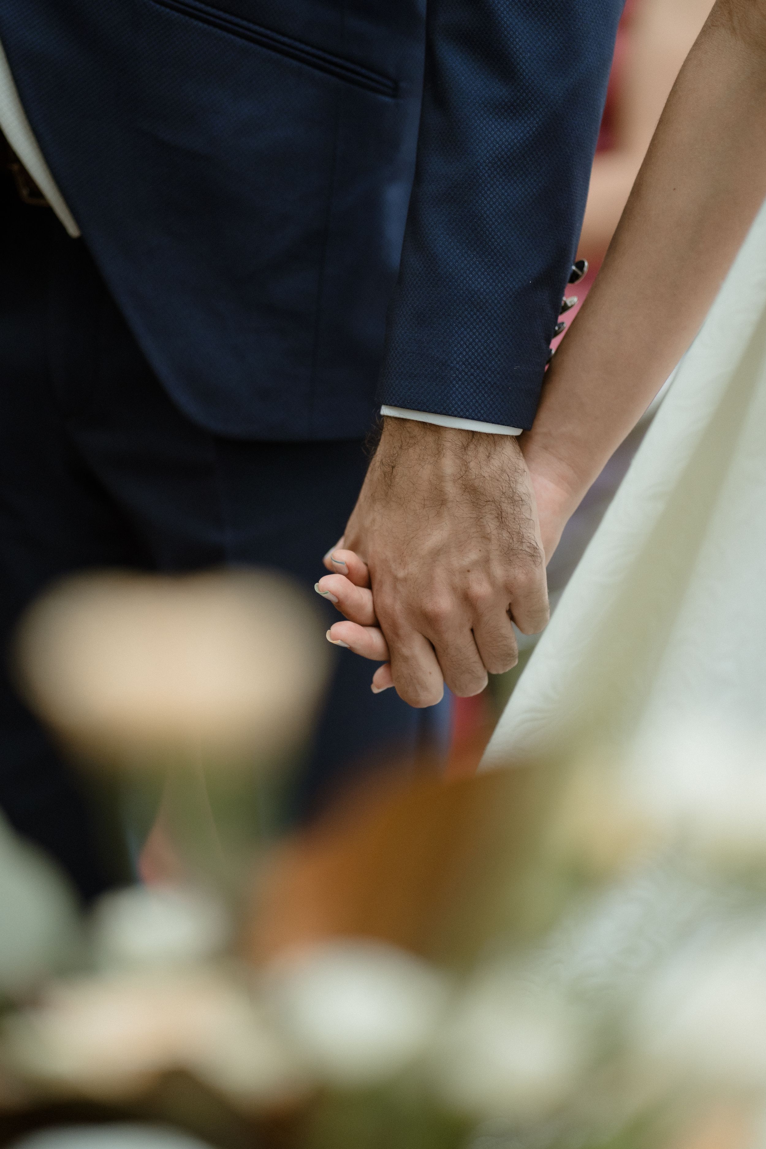 Close-up of hands during an intimate wedding ceremony moment.