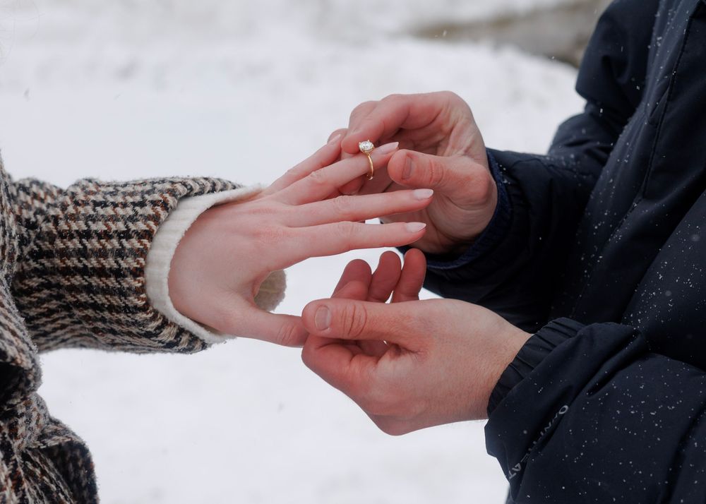 Close-up series of hands exchanging a diamond ring during a winter proposal against a snowy background.