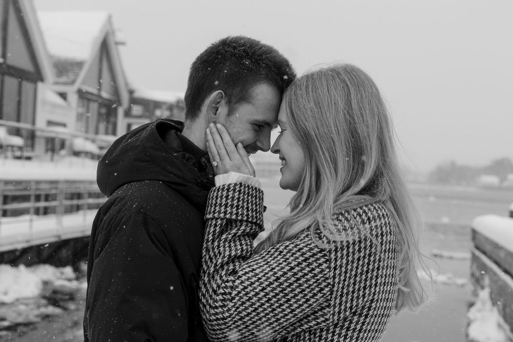 A romantic black and white photo of a couple sharing an intimate moment outdoors in winter wearing cozy coats.