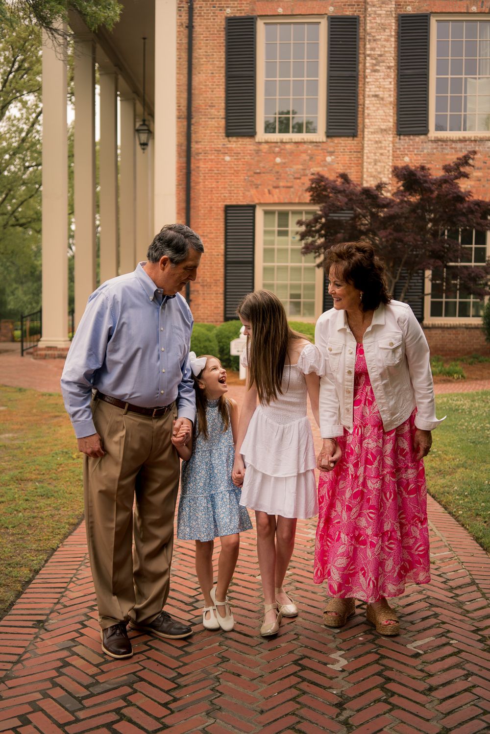 Four sequential photos show people walking together on a brick pathway outside a traditional brick building.