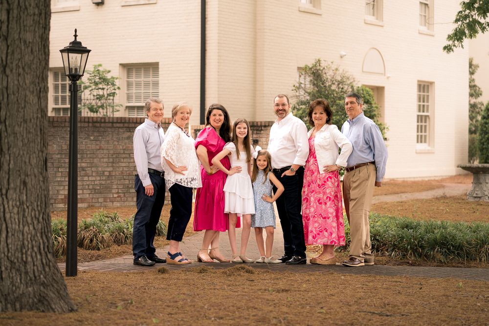 Extended family gathering posed together outside a historic brick building.