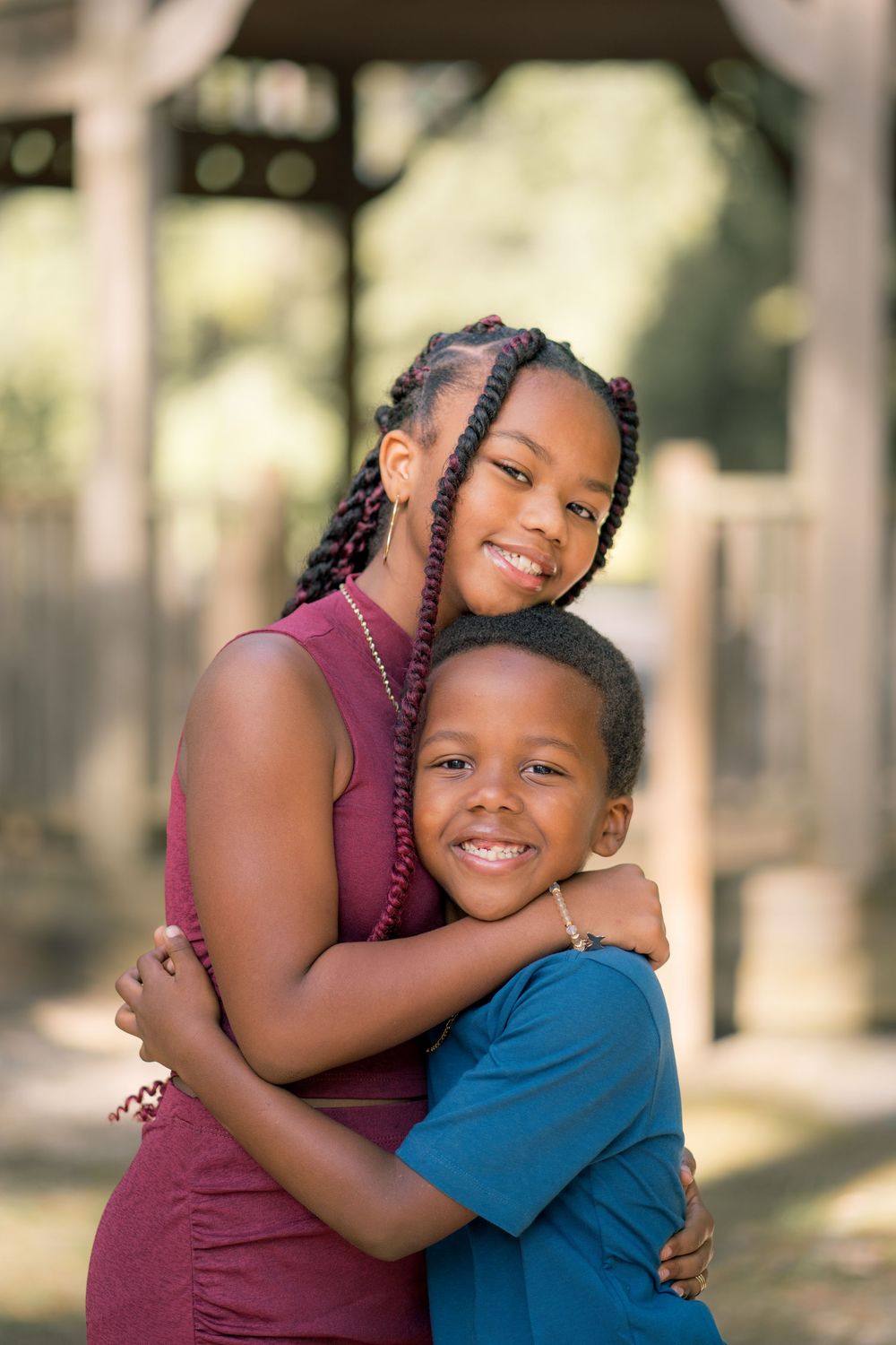 Sweet embrace between two people in burgundy and blue outfits during outdoor portrait session.