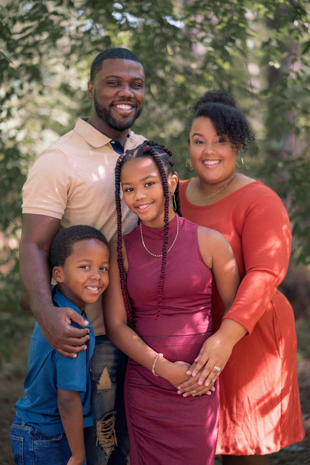 Family of four poses together outdoors in coordinated casual outfits.