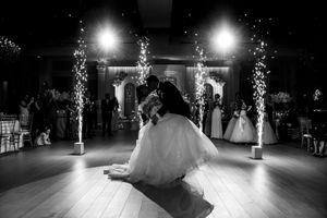 Groom dips bride in romantic black and white first dance photo with sparkler fountains at wedding.