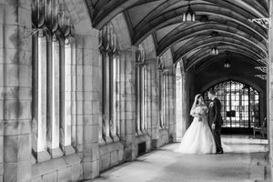 Bride and groom sharing romantic moment in black and white photo inside Gothic stone archway.