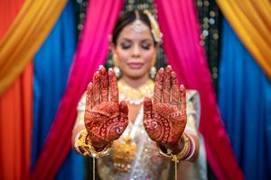Indian bride displays intricate henna mehndi designs on both hands during traditional pre-wedding ceremony.