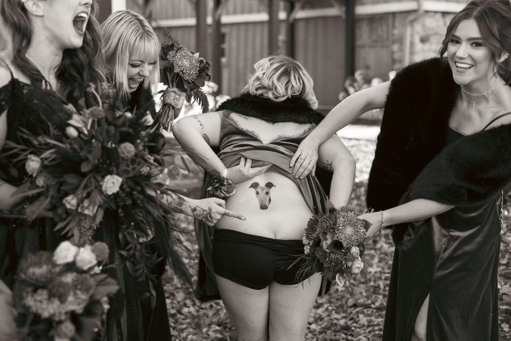 Black and white photo of friends showing belly painted like a basketball in playful outdoor photo shoot.