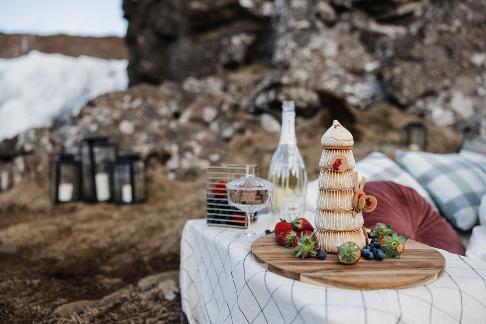An elegant outdoor picnic setup with drinks and snacks against a rocky backdrop.