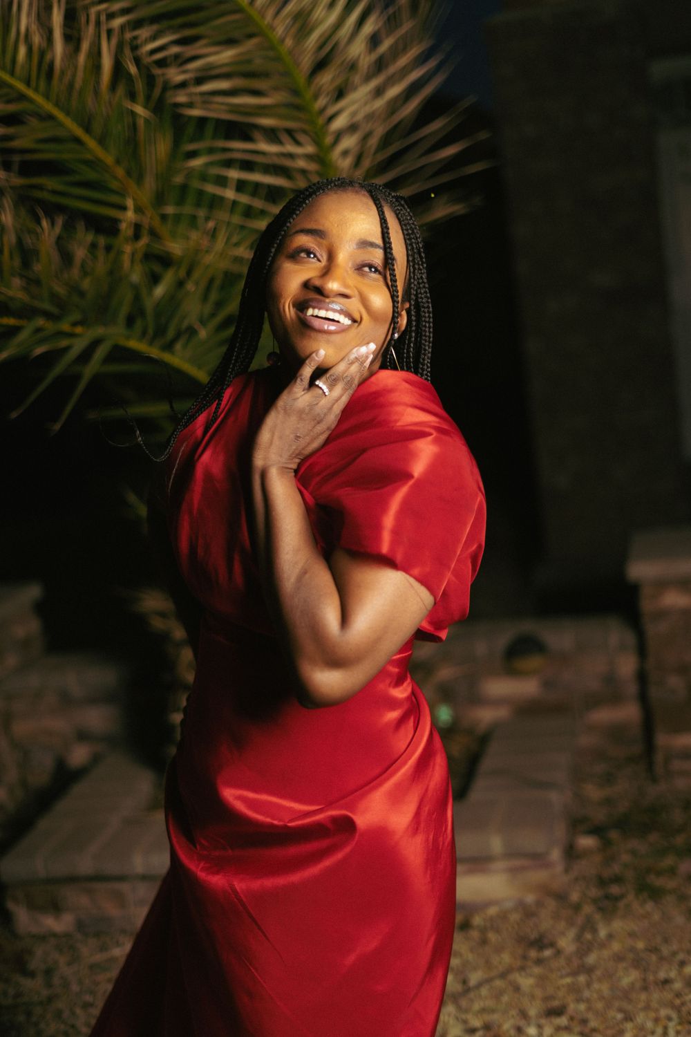 Candid outdoor portrait showing joyful expression in red formal dress.
