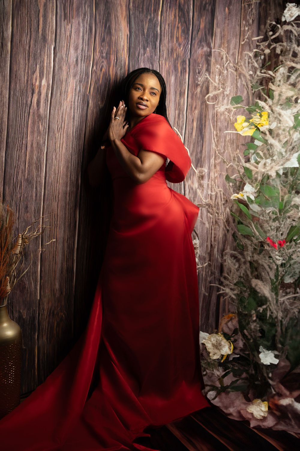 Portrait series against wooden wall with floral accents and person in elegant red dress.
