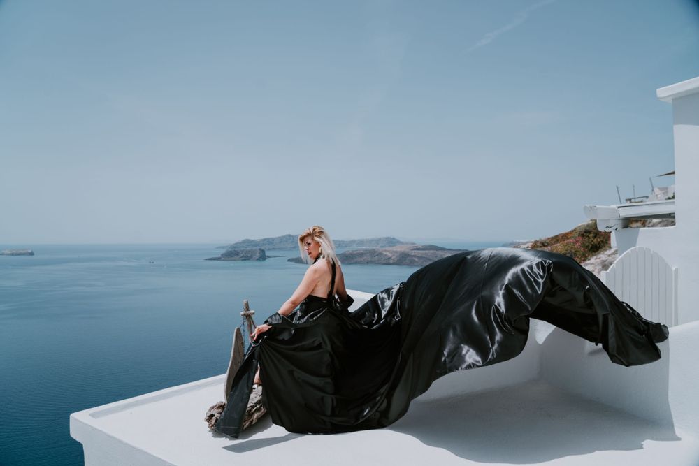 Black fabric creates artistic movement against crisp white architecture and Mediterranean views.