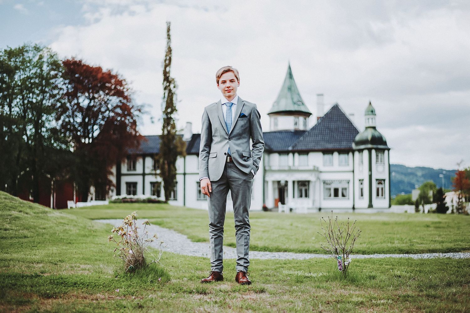 A formal portrait in front of a grand mansion with turrets and manicured grounds.