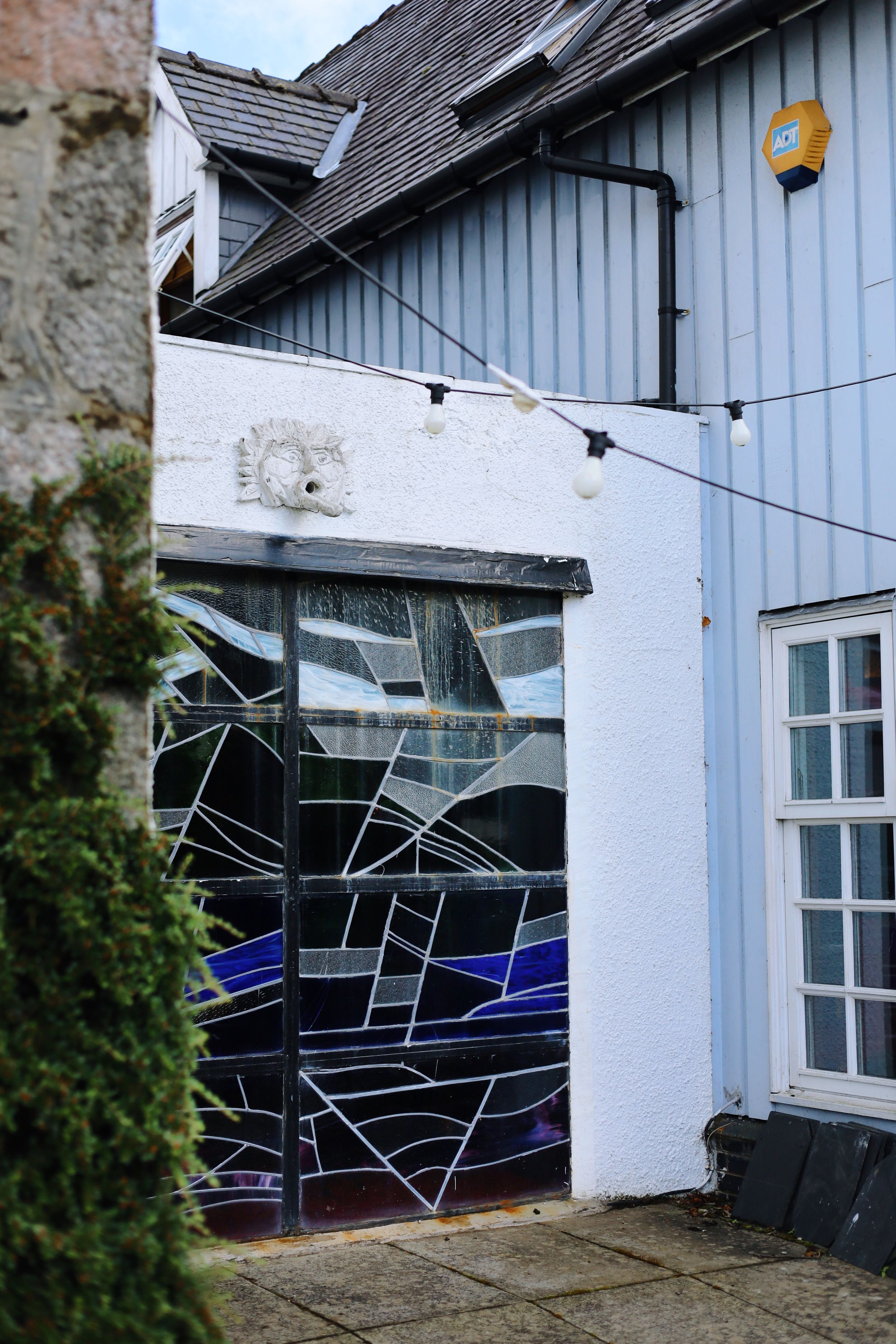 Contemporary art installation with geometric black spider web patterns on white exterior building walls.