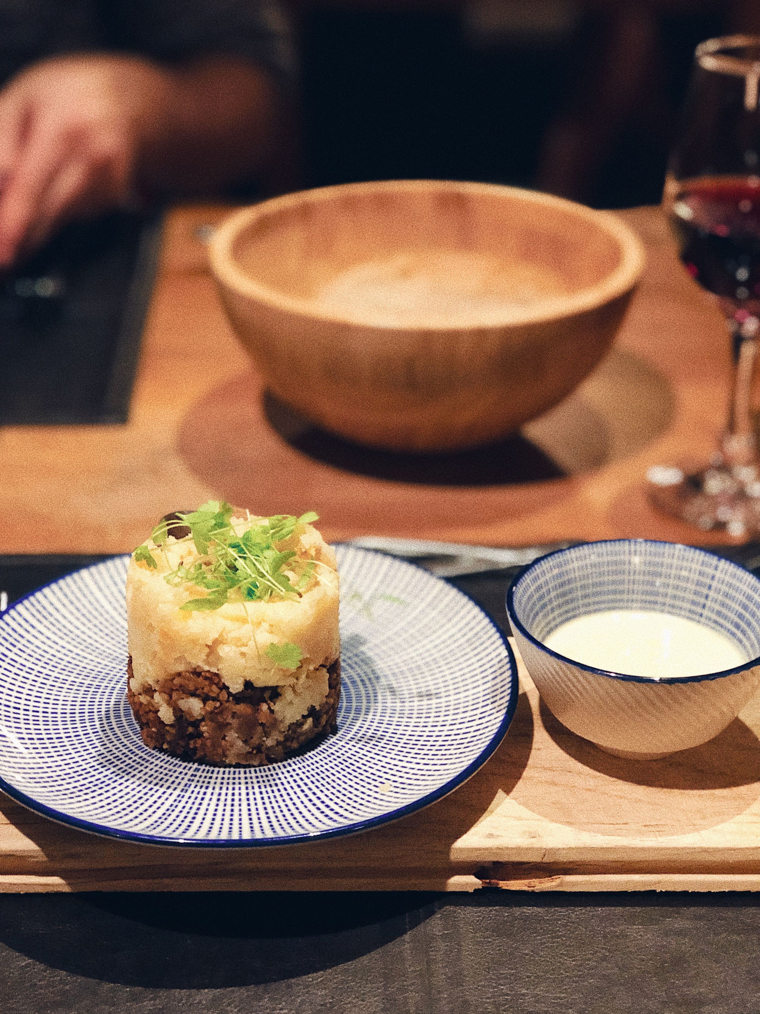 Series of plated dishes served on blue and white patterned plates with wooden serving boards.