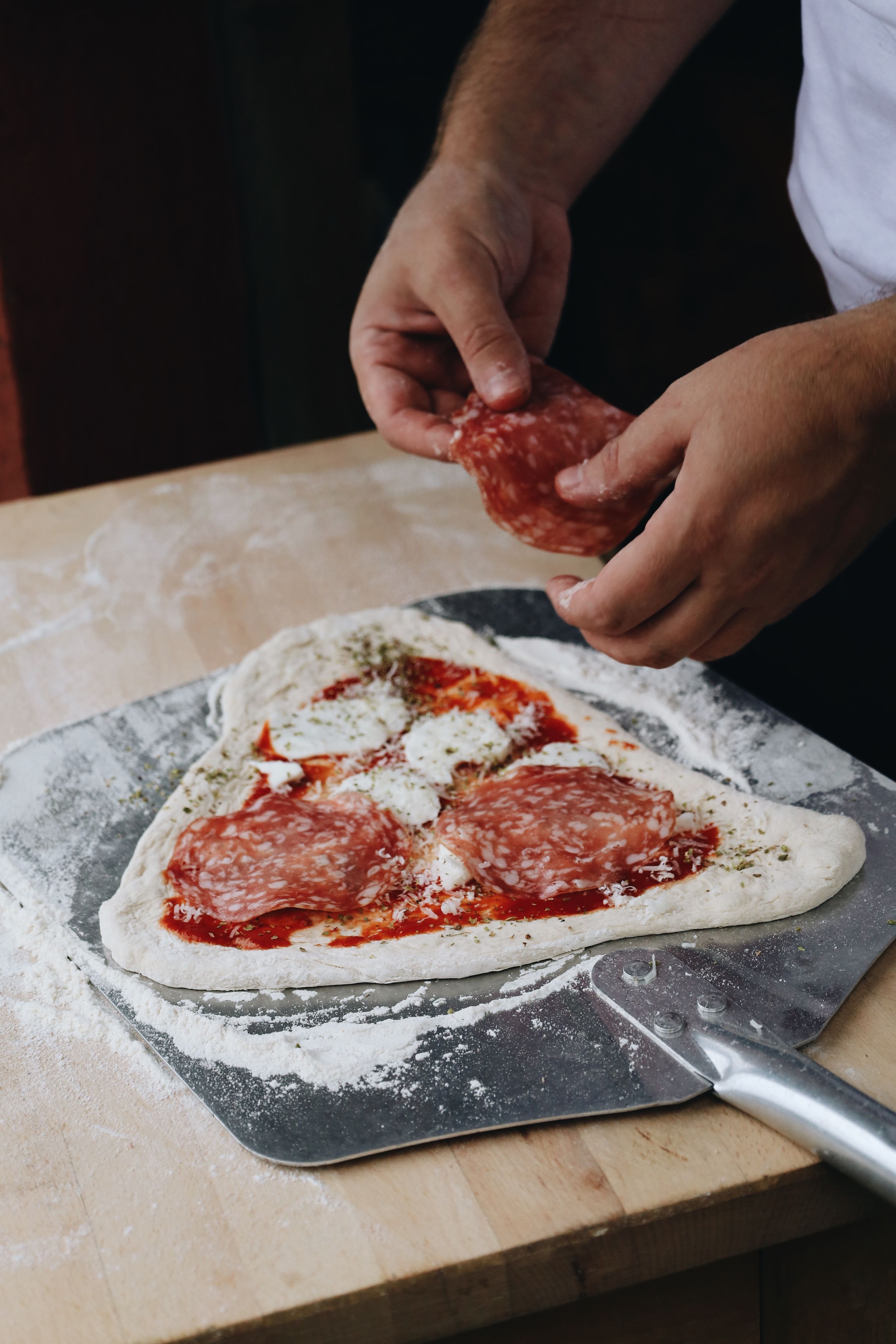 Step-by-step preparation of pizza dough and sauce on a floured wooden surface.
