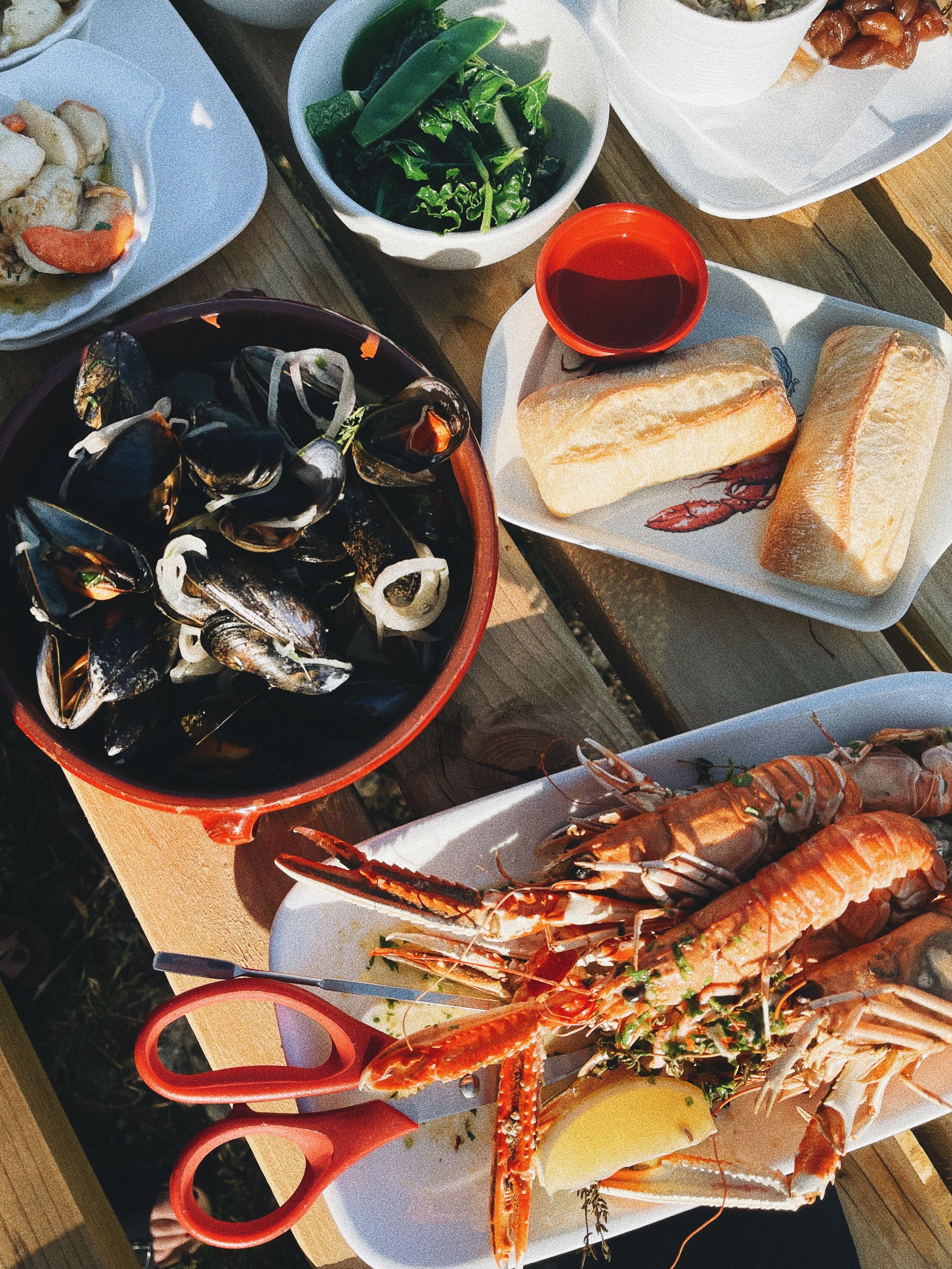 Seafood feast spread featuring lobster, mussels, and crusty bread on a dark table.