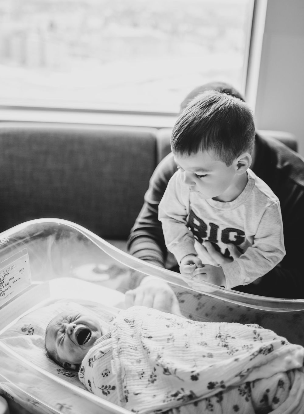 A sleeping baby in a white onesie lies on patterned fabric in a series of black and white photos.