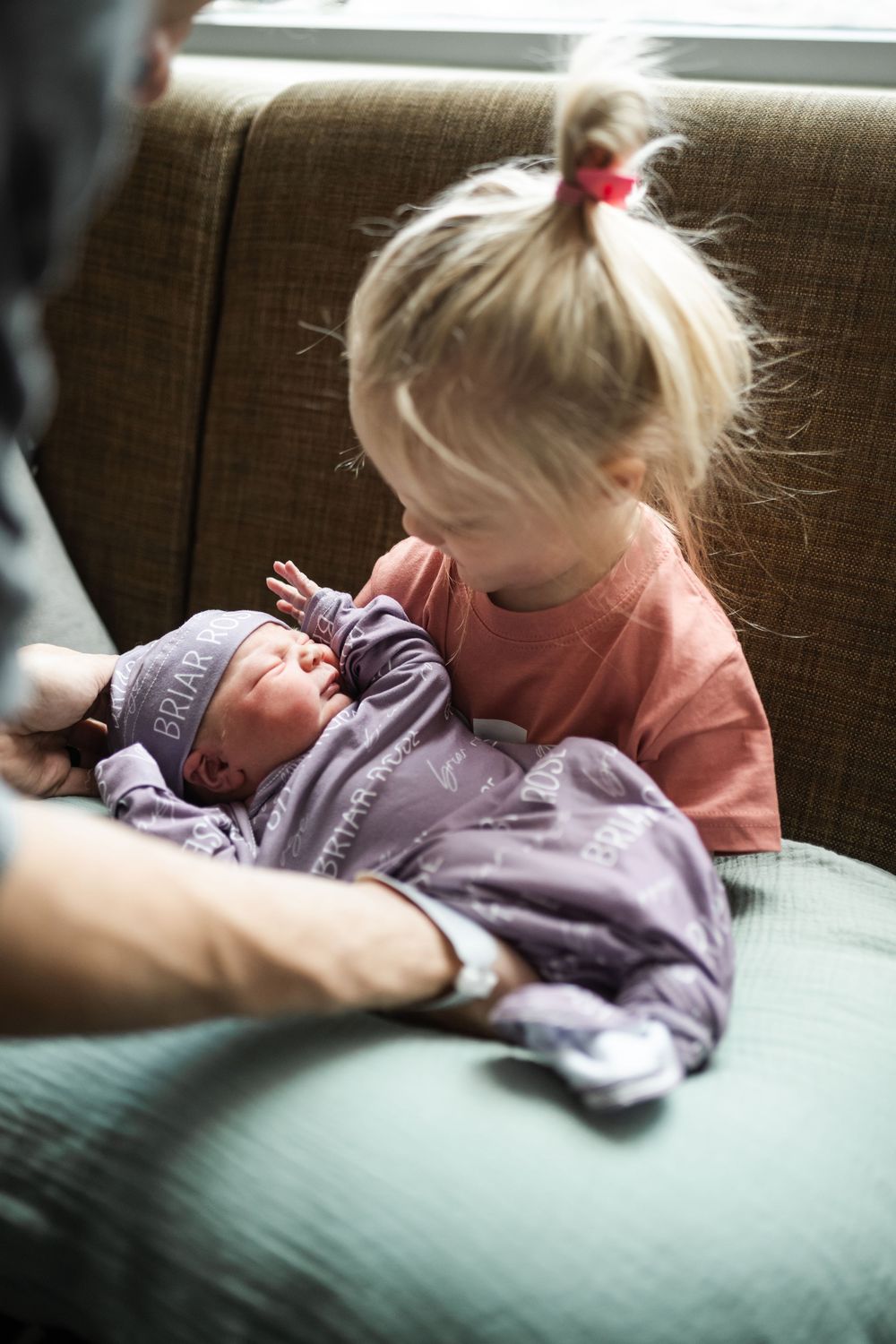 Young child resting on a grey couch in soft natural light.