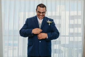 Person in navy blue suit adjusting tie while getting ready for wedding.