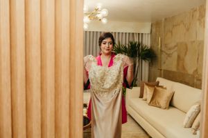 Wedding dress hanging on display in preparation room with warm lighting.