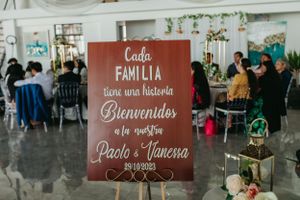 Wedding welcome sign in Spanish with red background at reception venue.