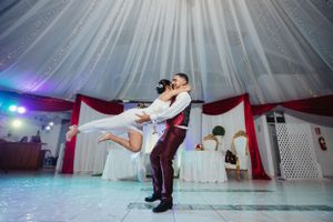Dramatic dance lift between couple during their wedding reception with atmospheric lighting.