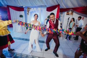 Energetic couple dancing under colorful paper decorations at their wedding celebration.