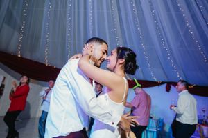 Intimate dance moment between couple under twinkling lights at wedding reception.
