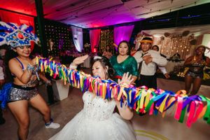 Wedding guests playing limbo with vibrant ribbons at a reception party.
