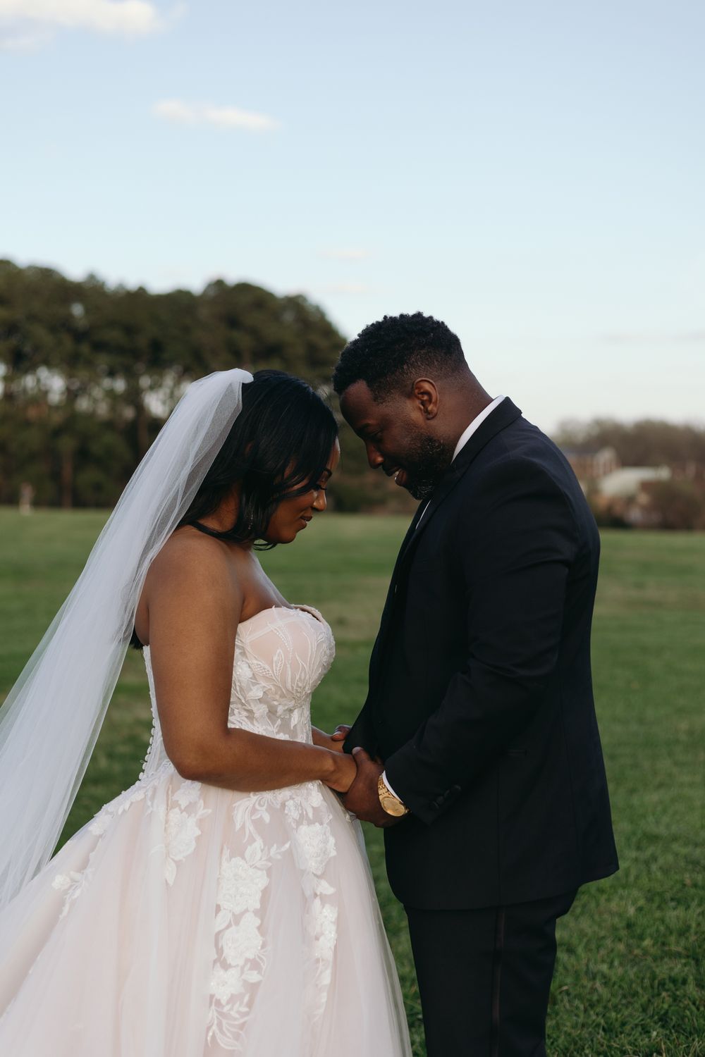 A new husband and wife hold hands and bow their heads in prayer after their wedding ceremony.