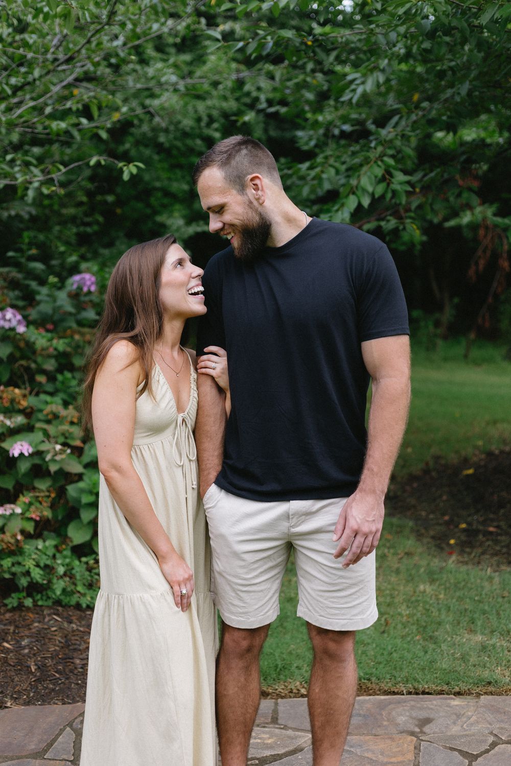 A couple with their arms linked look at each other and laugh together.
