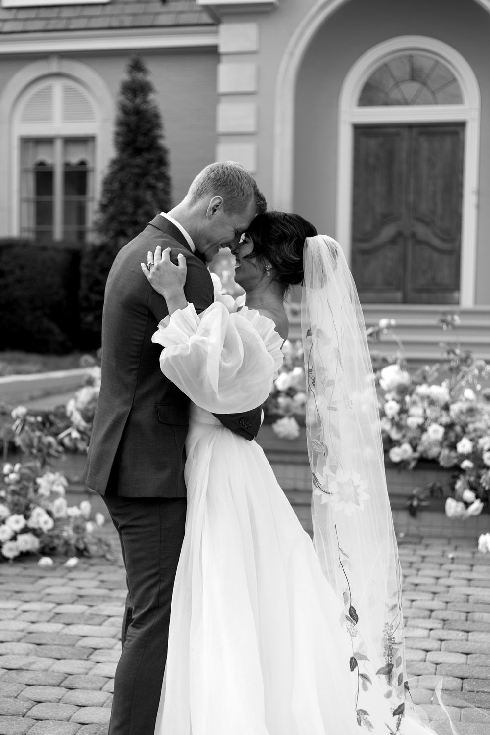 A bride and groom embrace and are about to kiss. Black and white.